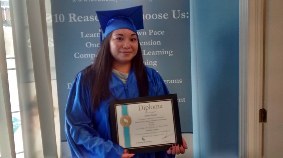 Graduate in cap and gown holding diploma certificate at Academy of Learning Career College