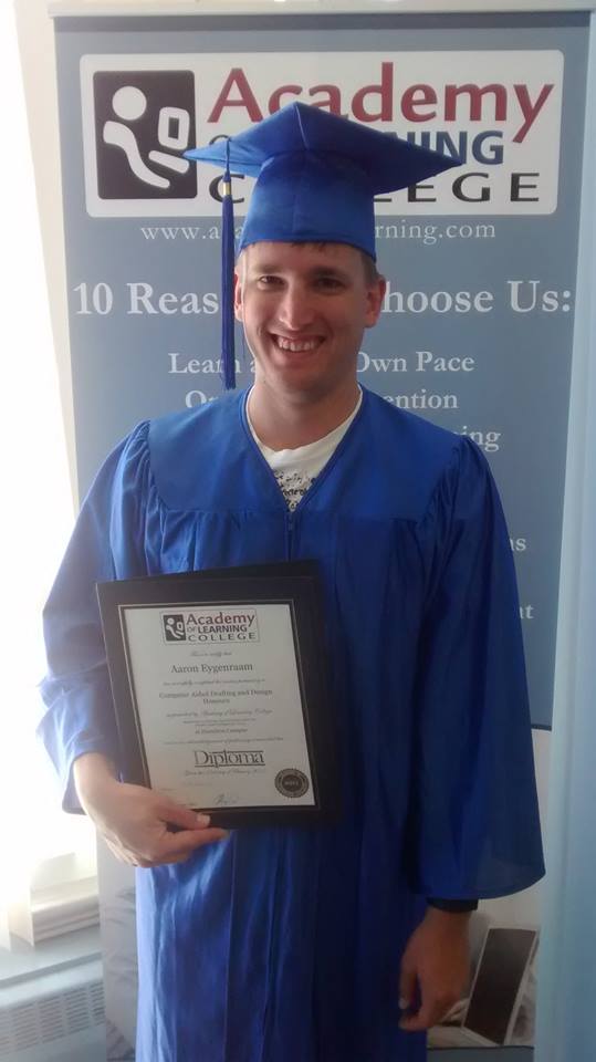 Male graduate wearing a blue cap and gown holding a diploma certificate in front of Academy of Learning College banner