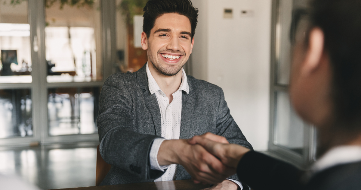 Job candidate giving firm handshake during successful interview with positive body language