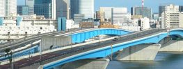 Urban skyline with blue highway bridge crossing river