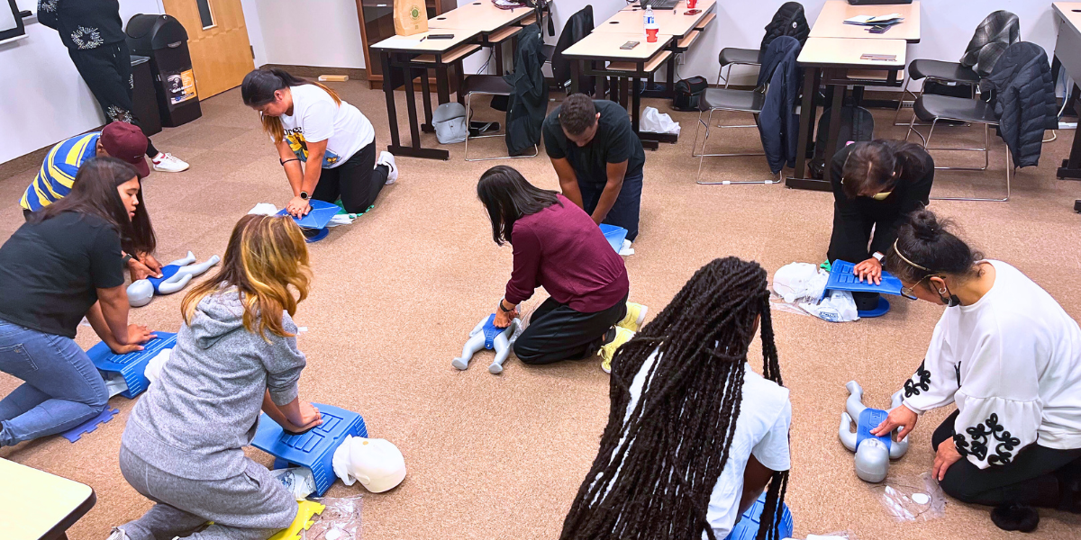 Students enrolled in an AOLCC health & wellness program practicing infant CPR, gaining life-saving skills as part of their health care diploma training.