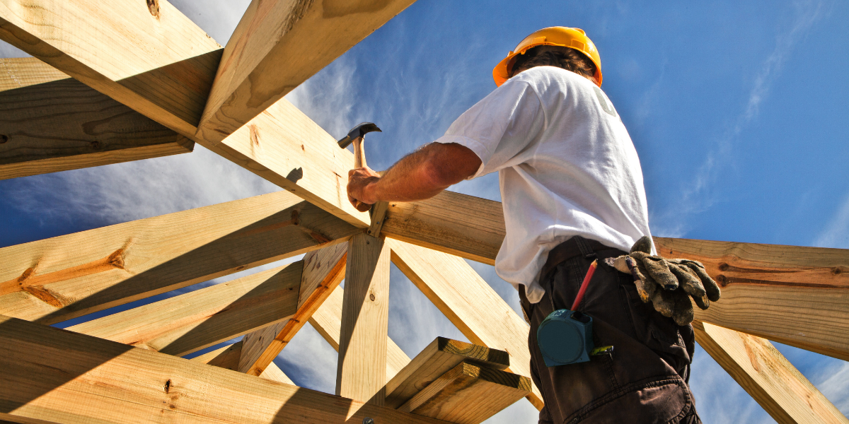 A carpenter measuring wood in a workshop, emphasizing hands-on skills learned in a one-year certificate program for construction careers.