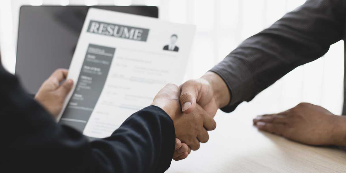 A happy individual shaking hands with an employer, celebrating a successful job offer after unemployment.
