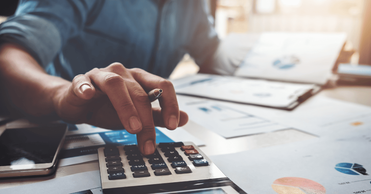 Accountant performing calculations on financial data with calculator and business charts